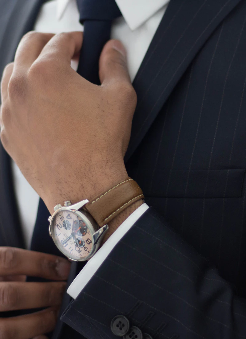 Close detail of a dark tailored suit and wristwatch
